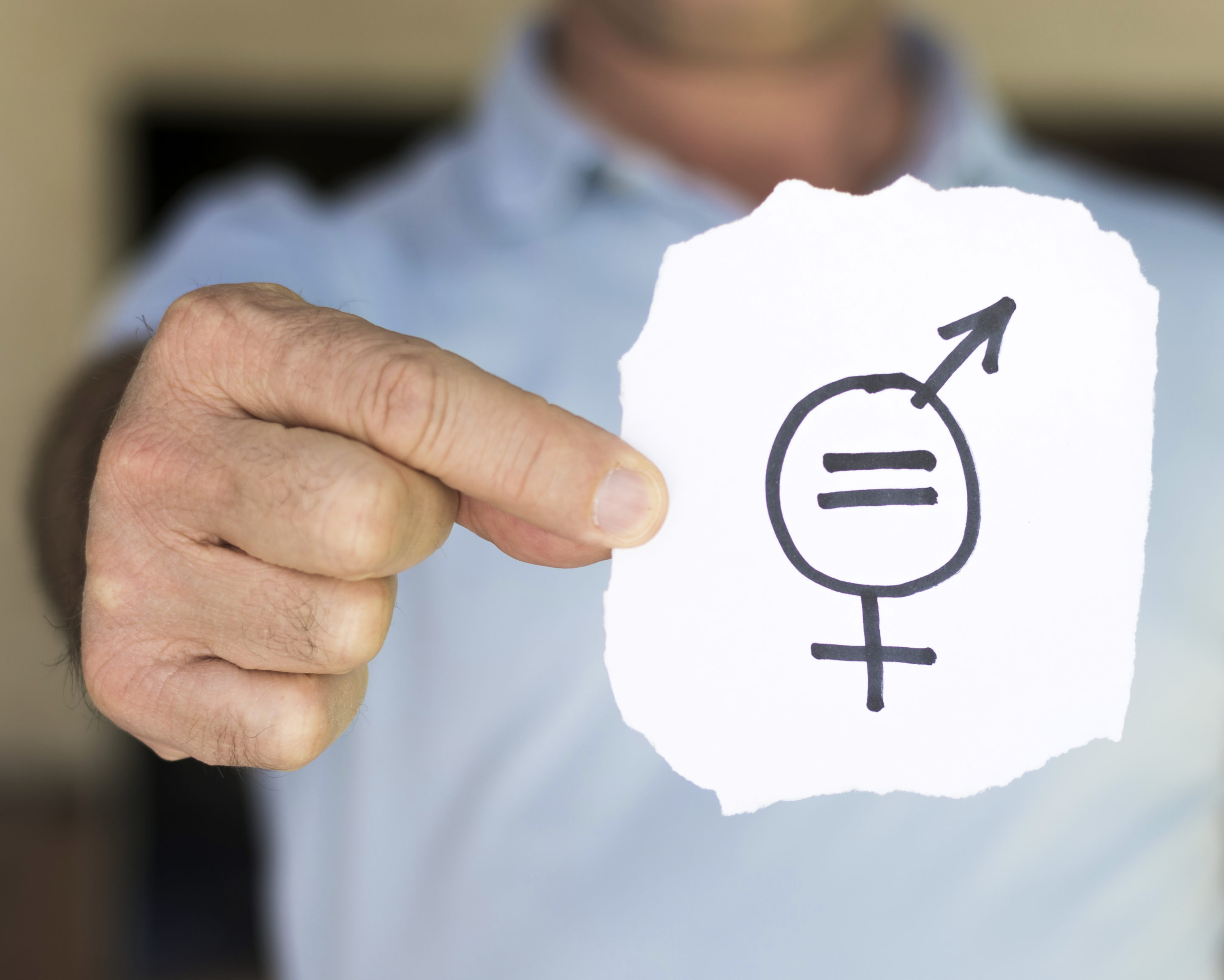Plan de Igualdad en las empresas; en la imagen se ve a un hombre sujetando un papel con un dibujo que mezcla el símbolo de hombre y de mujer