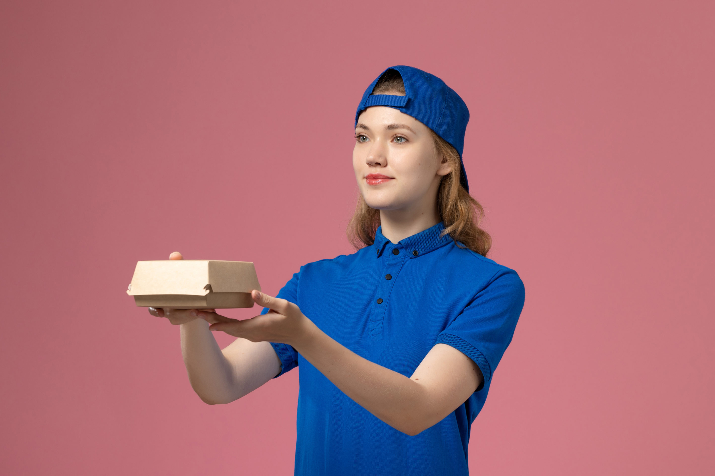 trabajadora de restaurante de comida rápida sujetando una caja de cartón para hamburguesa; para el artículo de Debido a los riesgos de trabajar en un restaurante de comida rápida