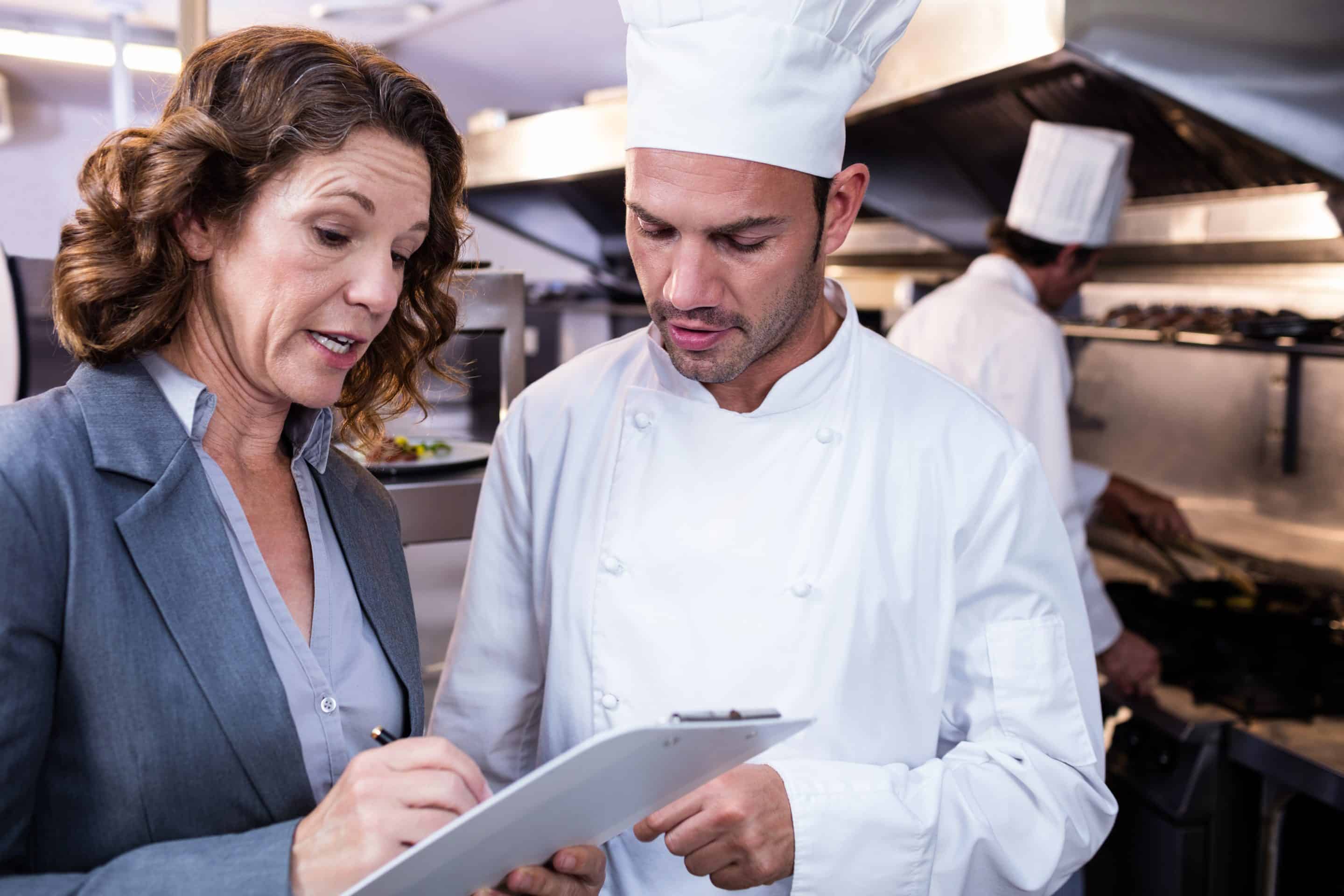 Female restaurant manager writing on clipboard while interacting to head chef in commercial kitchen Fenómenos meteorológicos adversos